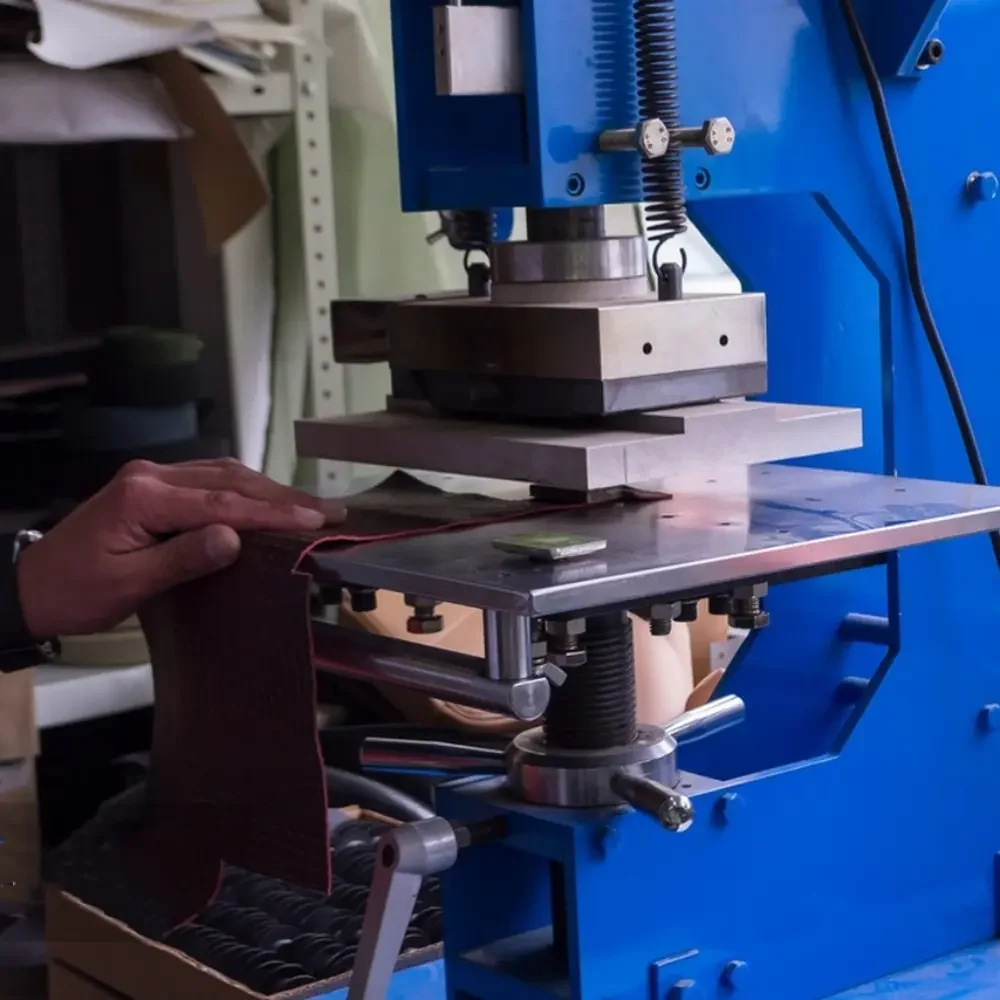 This image shows a DC shunt manufacturing process where a technician is manually guiding a sheet of Manganin or a similar resistive material through a press machine. This step is likely for cutting or shaping the material into the precise dimensions required for shunt resistors, an essential part of ensuring the accuracy and reliability of the final product.