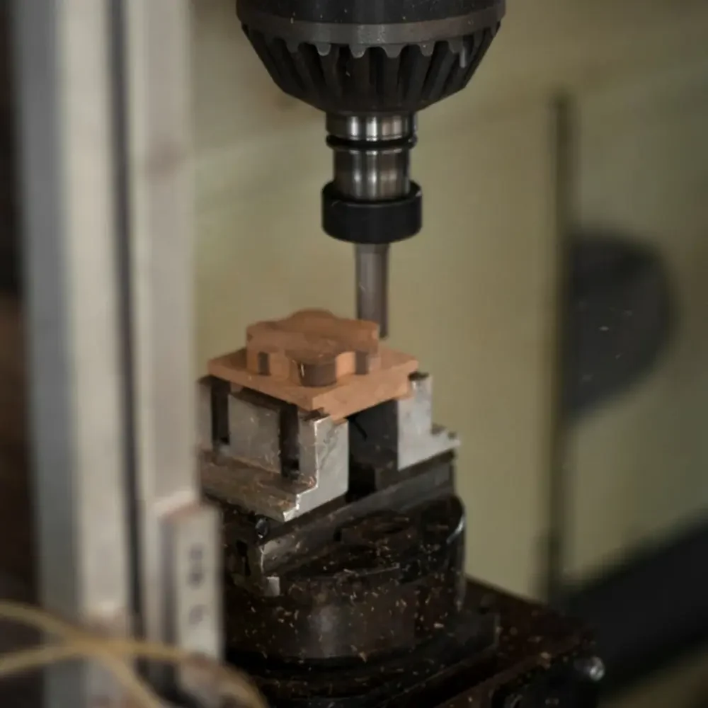 The image captures a detailed view of a DC shunt component being precisely machined with a drill press. The shunt is clamped securely, illustrating the meticulous process involved in shaping and creating components that will be used for accurate electrical current measurements.